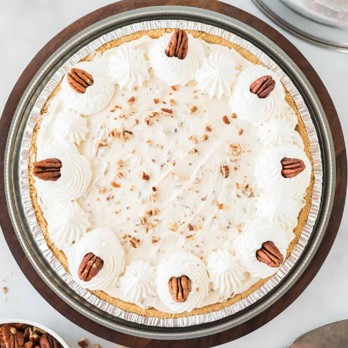 pecan cream pie decorated with whipped cream and pecans on top