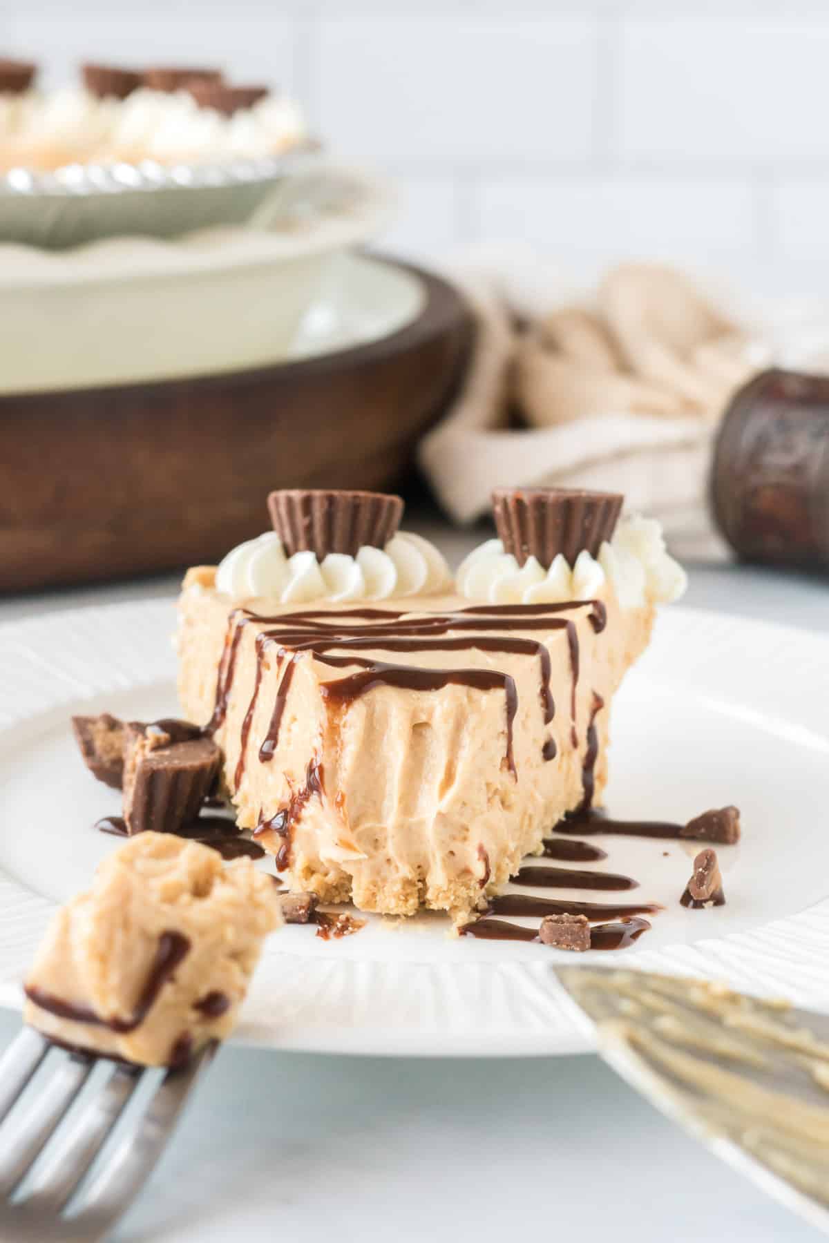 peanut butter pie slice on a plate drizzled with chocolate with a bite taken out