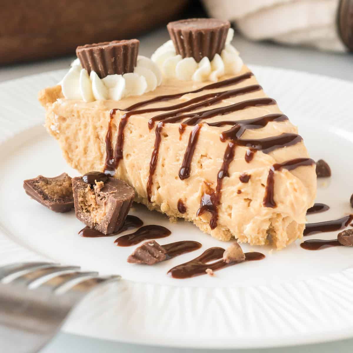 slice of peanut butter pie garnished with chocolate syrup and mini reese's cups