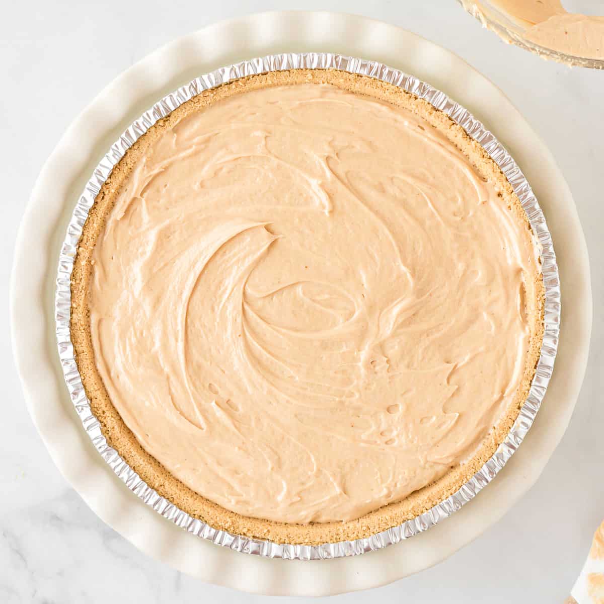 no bake peanut butter pie smoothed out in the graham cracker crust