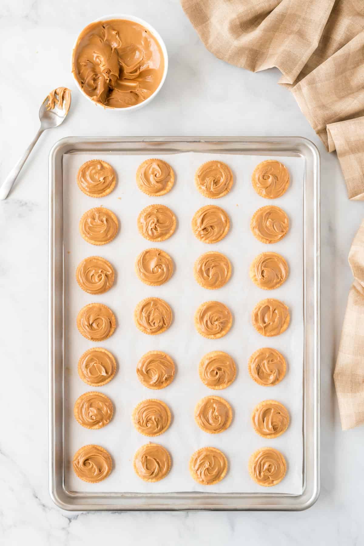 ritz crackers on a baking sheet topped with peanut butter