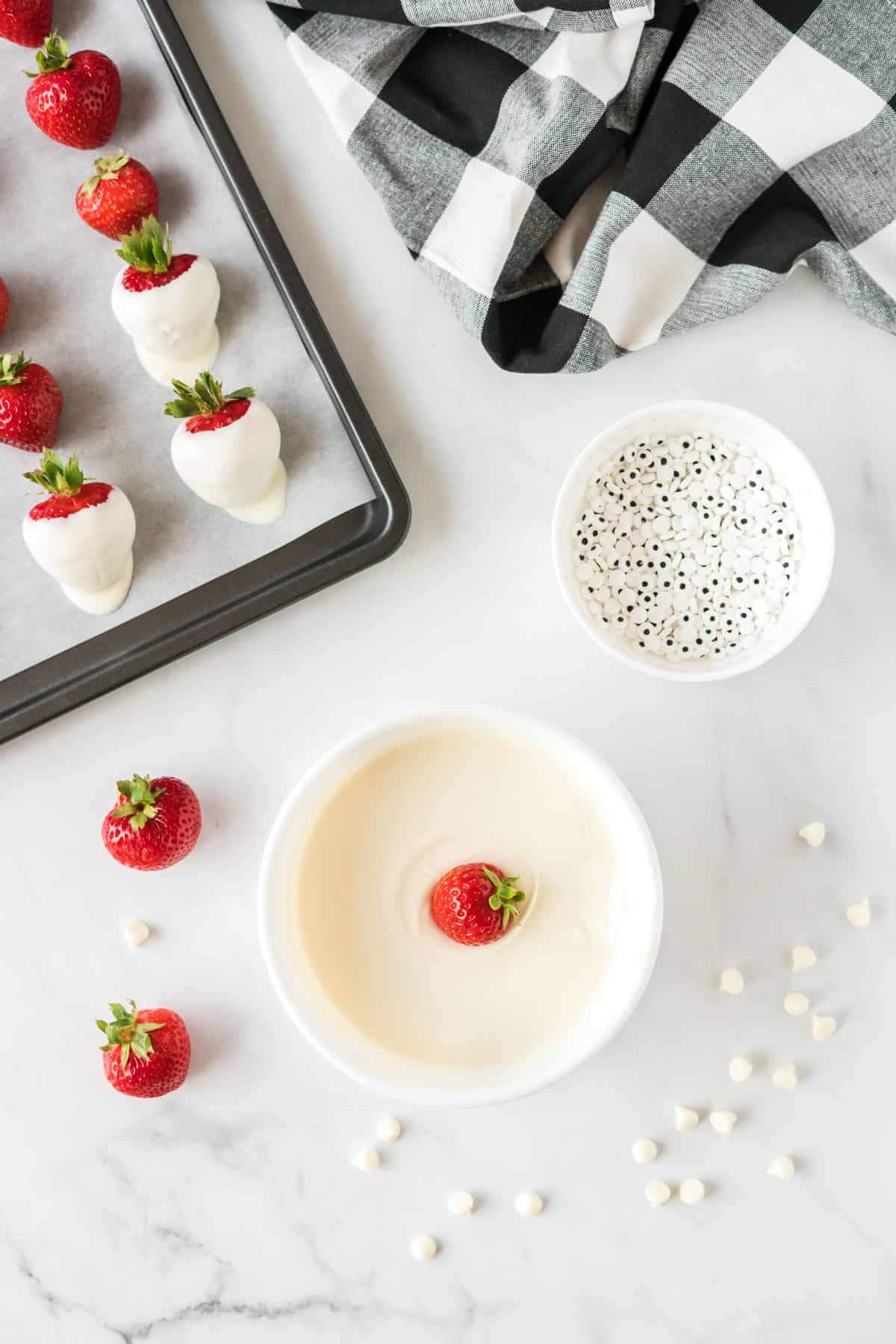 strawberry being dipped into white chocolate in a bowl