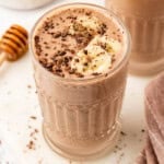 chocolate peanut butter banana smoothie topped with chocolate shavings and banana slices