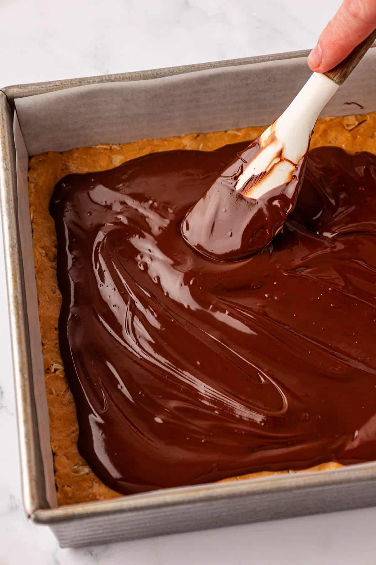 spreading the melted chocolate over the protein bars