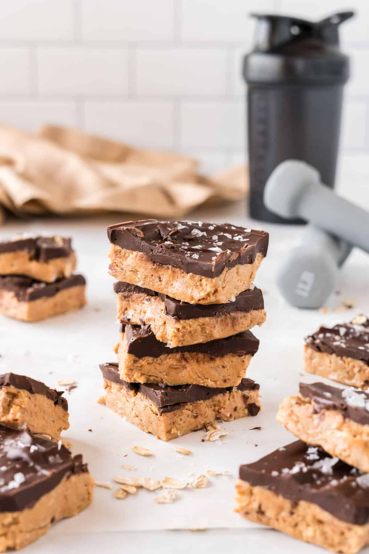 stacked protein bars with weights and a shaker bottle in the background