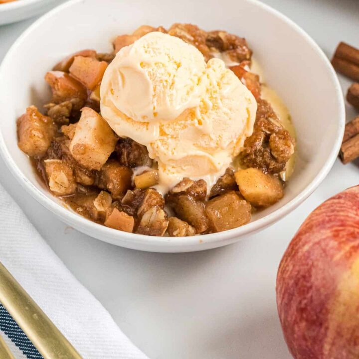 vegan apple crisp in a bowl topped with dairy free ice cream