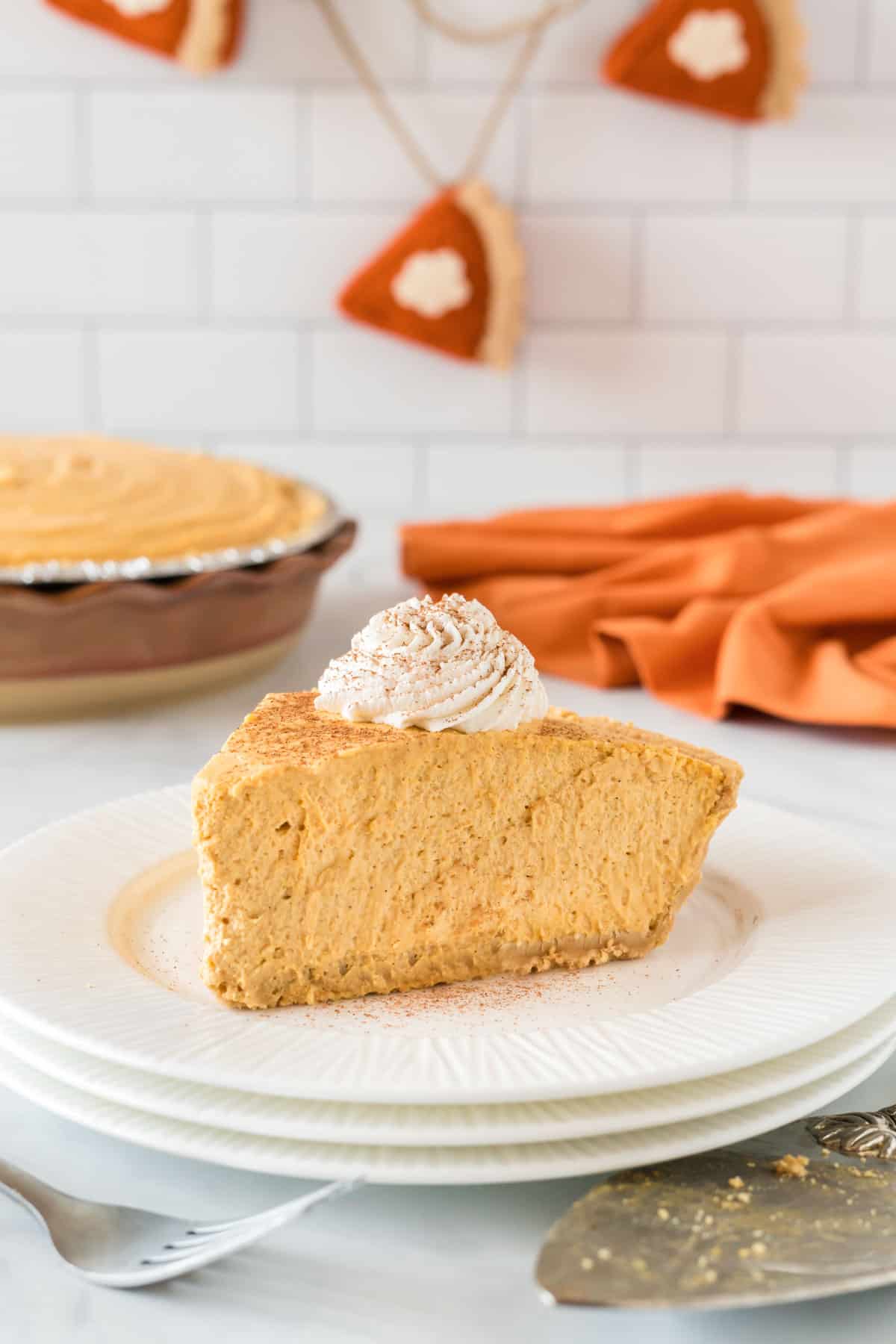 no bake pumpkin pie slice on a plate topped with whipped cream