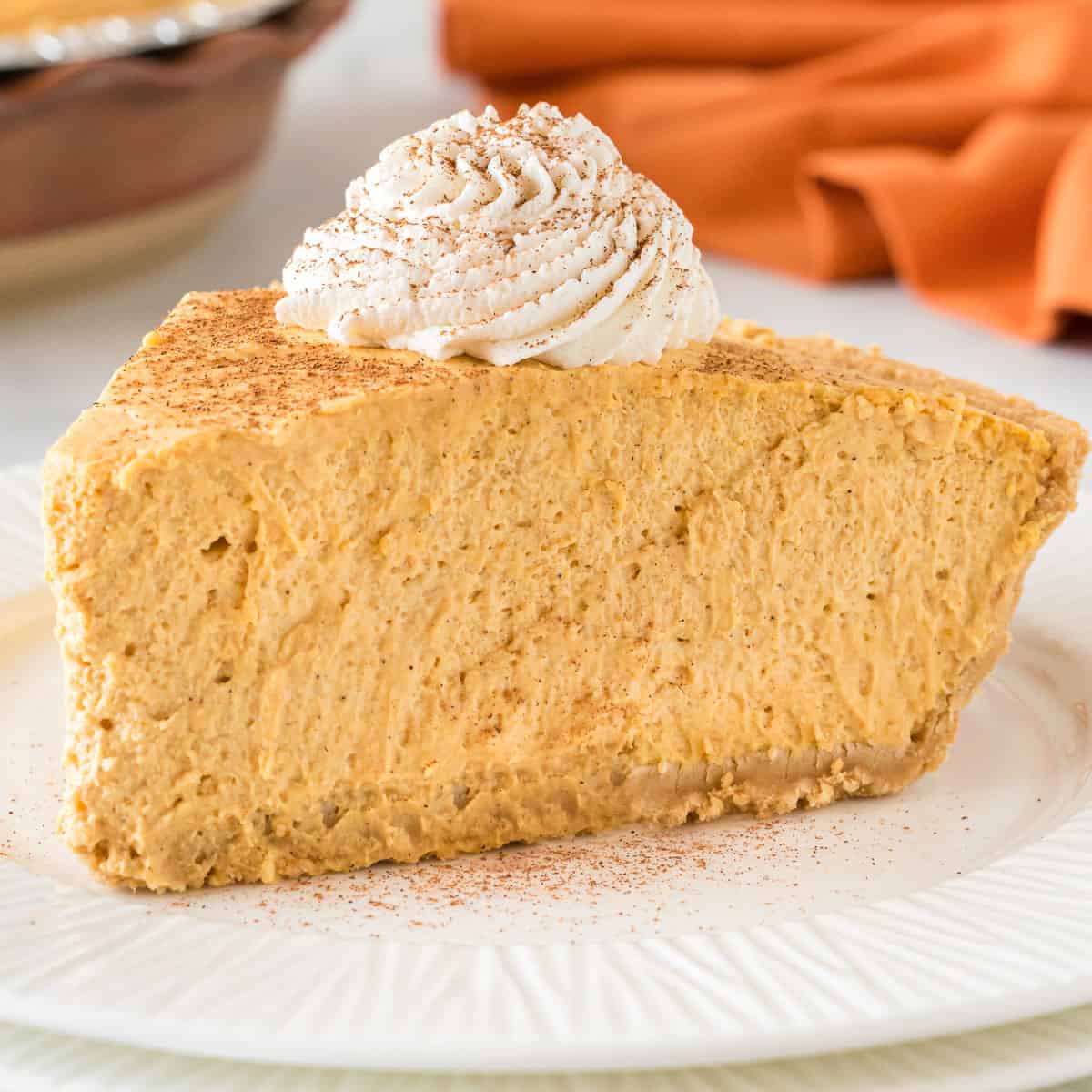 no bake pumpkin pie slice on a plate topped with whipped cream