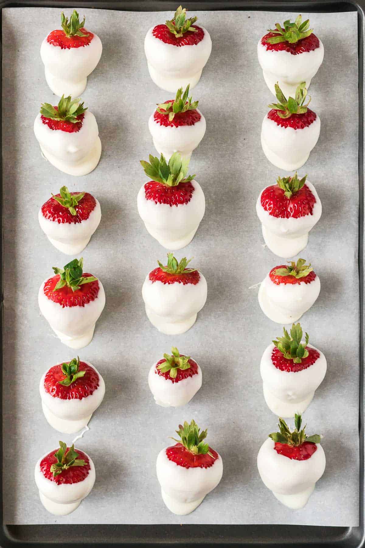dipped white chocolate strawberries on a baking sheet