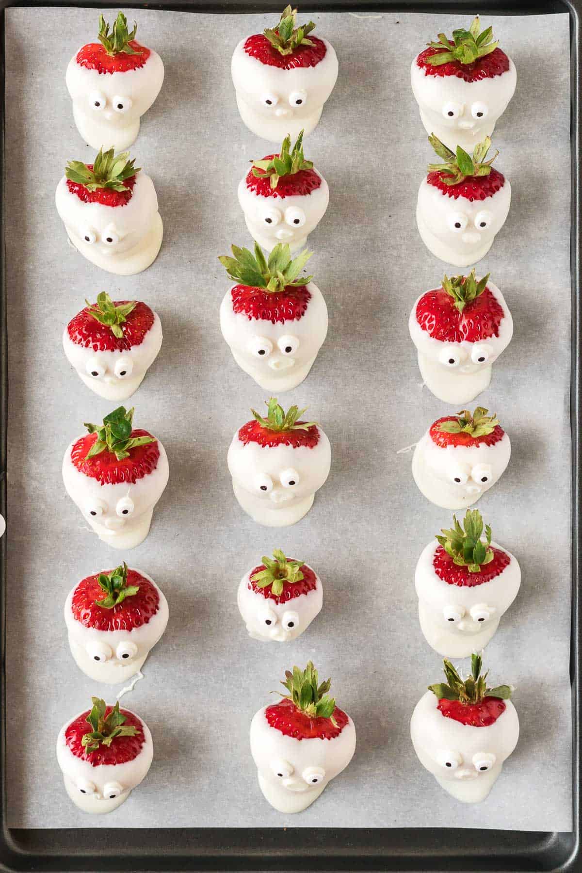 strawberry ghosts with candy eye balls on a baking sheet