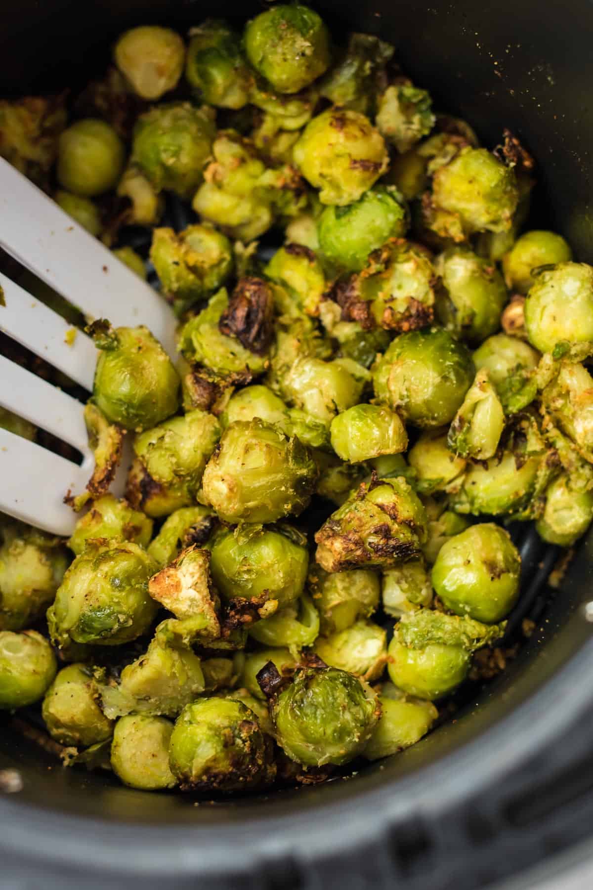 spatula taking a scoop of brussel sprouts from the air fryer