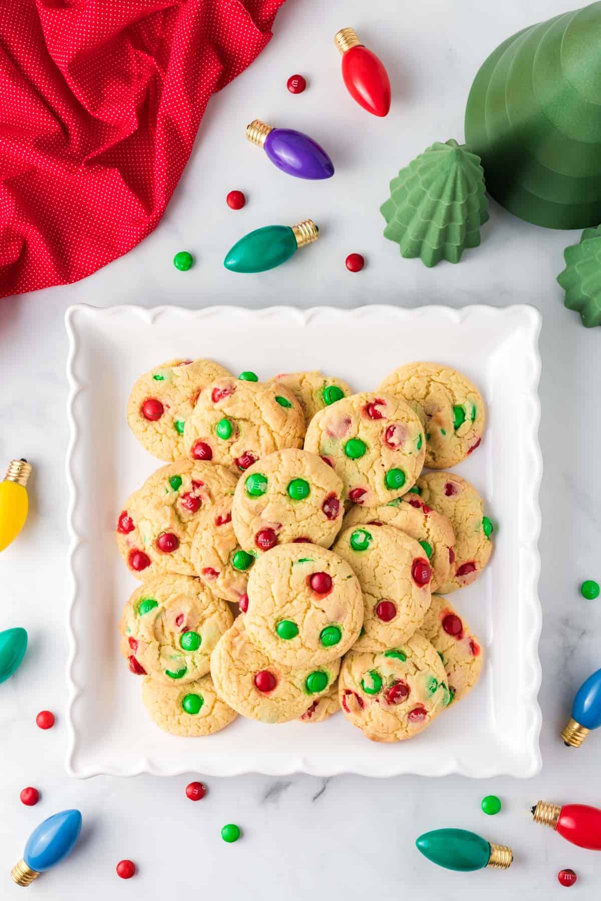 Christmas cookies on a white serving platter surrounded by holiday decorations