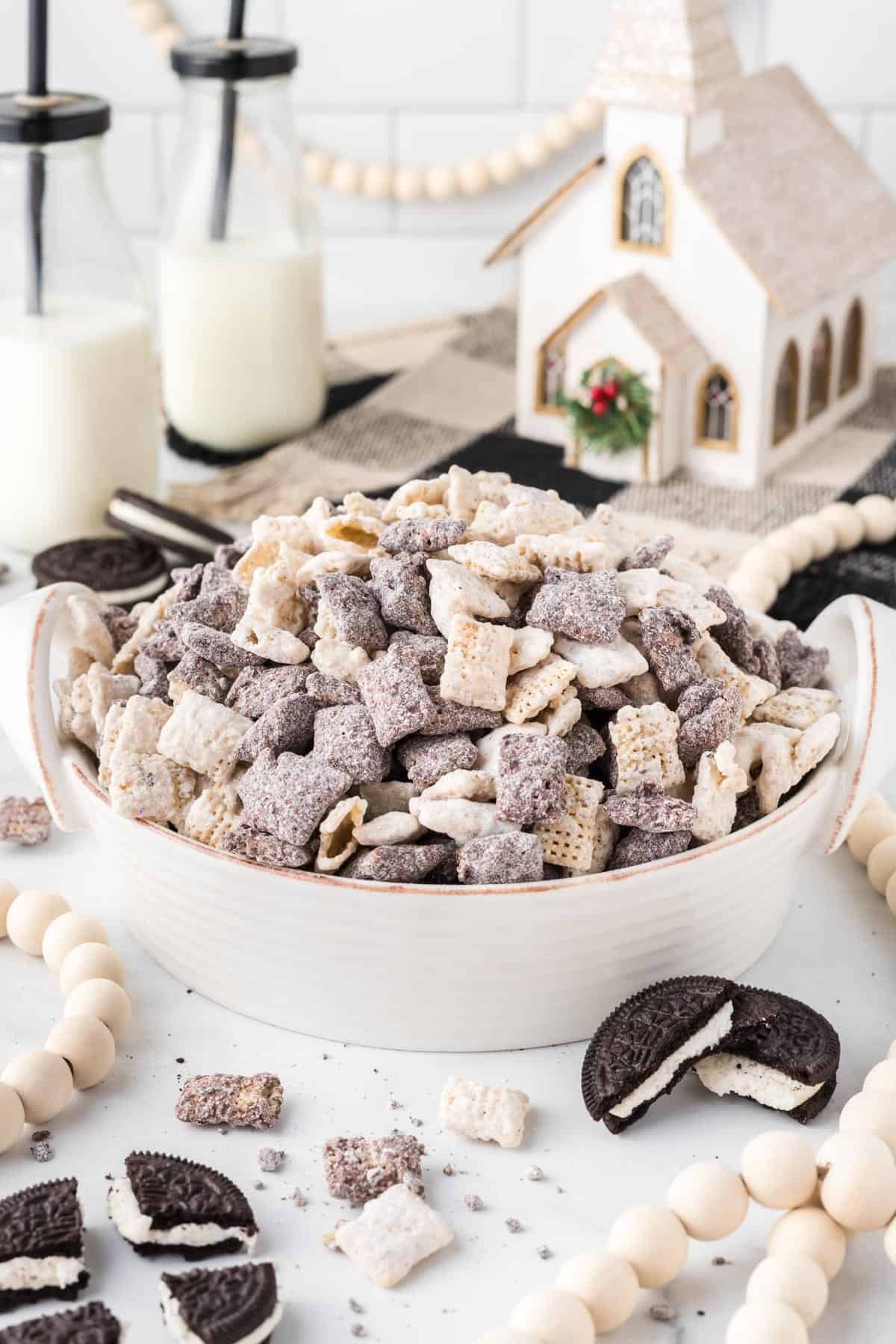 cookies and cream muddy buddies in a large serving bowl with Christmas decorations in the background
