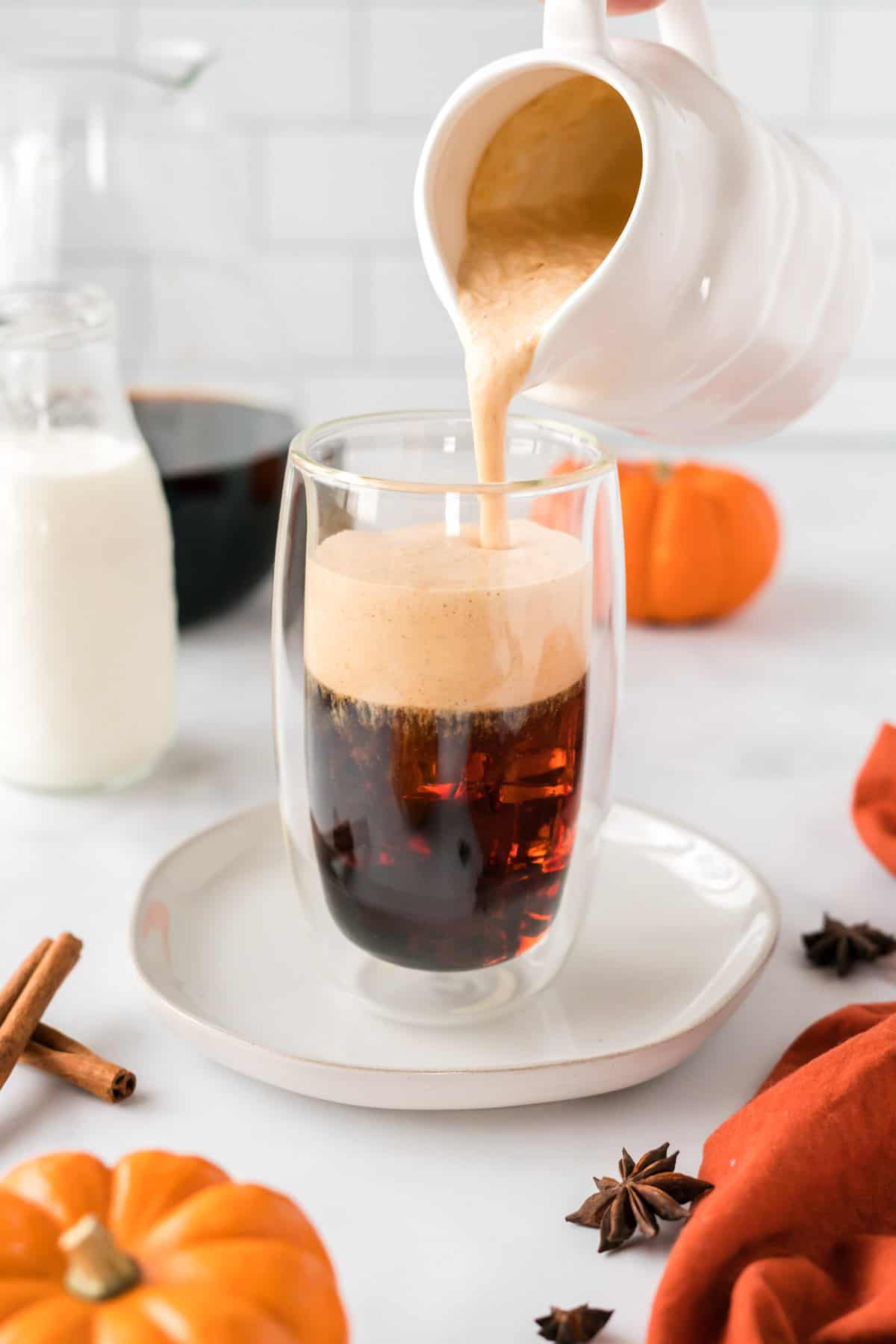 pouring pumpkin cream over cold brew coffee
