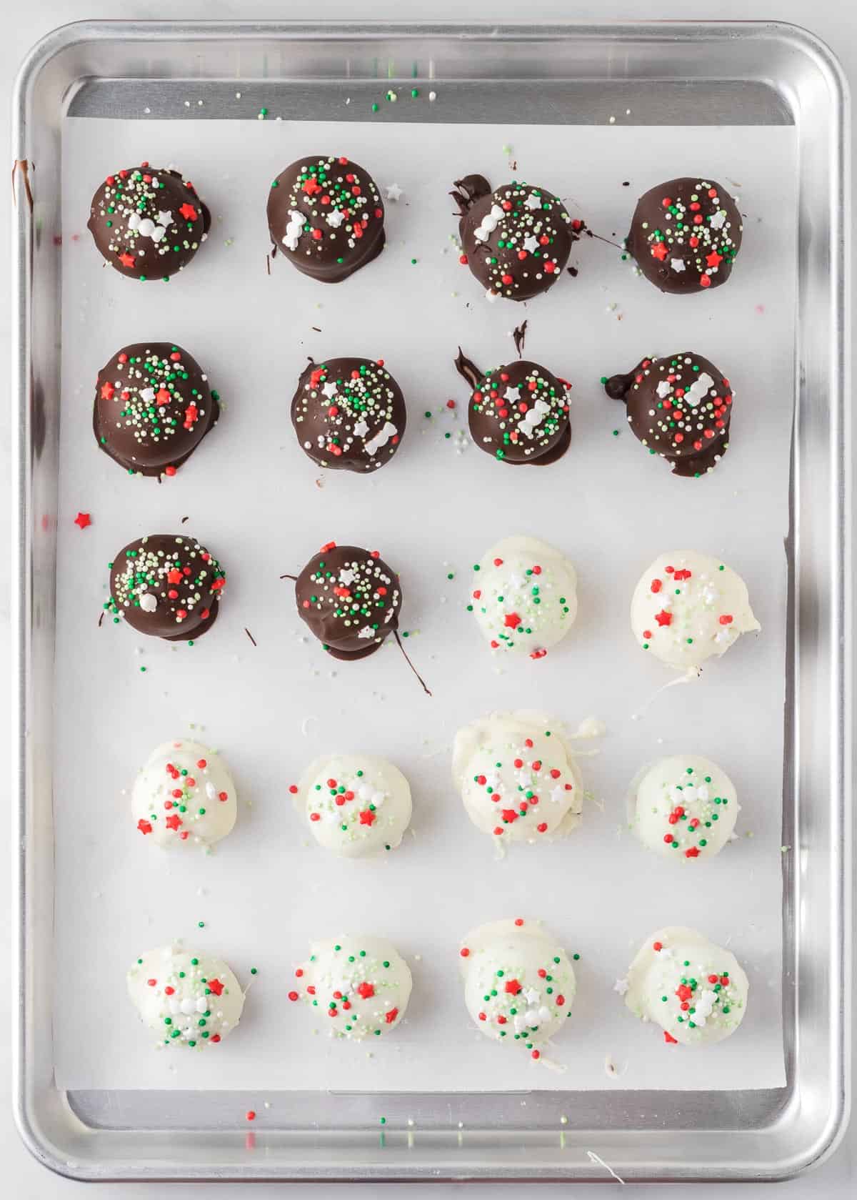 dipped oreo balls on a baking sheet topped with Christmas sprinkles