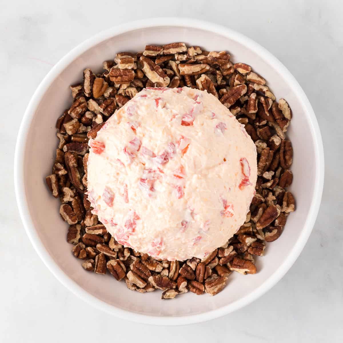 cheese ball over a bowl of pecan pieces