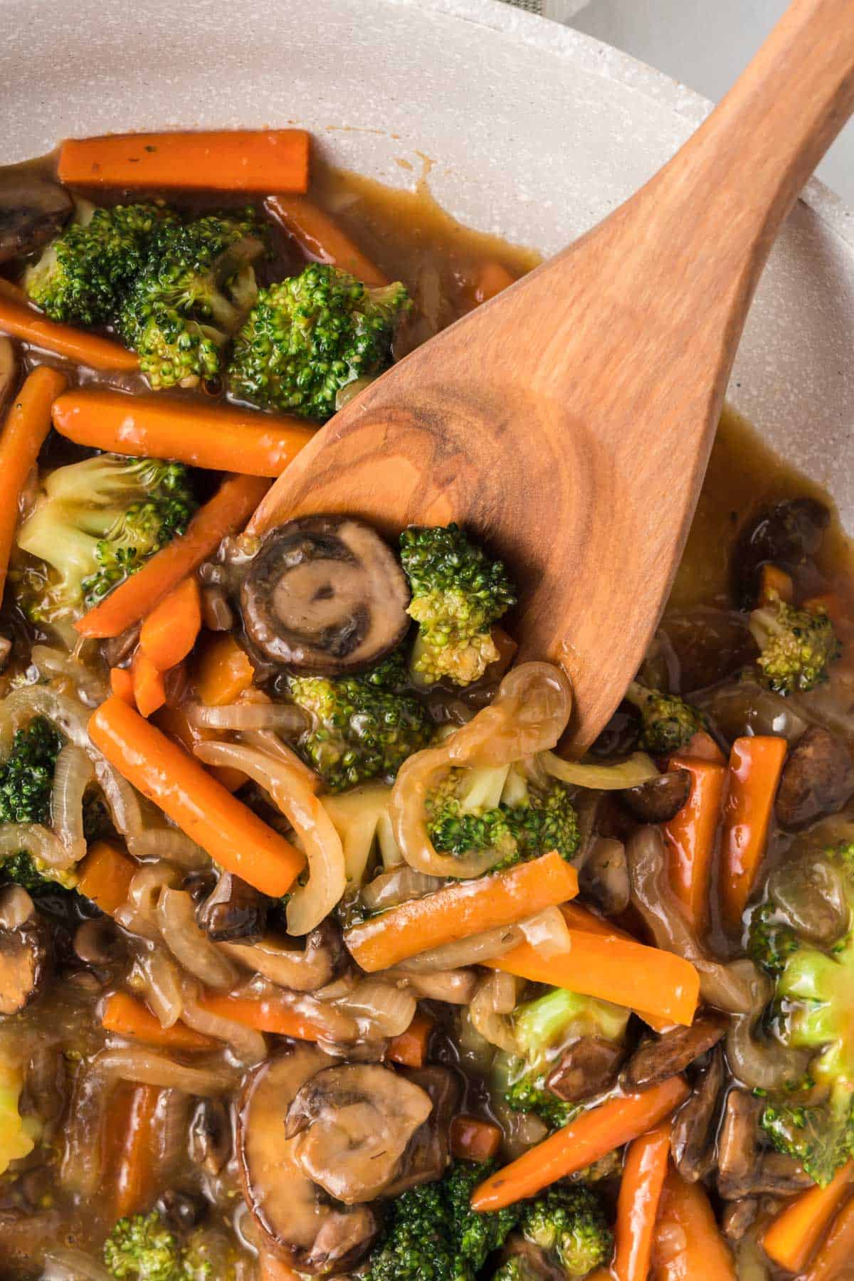 wooden spoon taking a serving of teriyaki vegetables