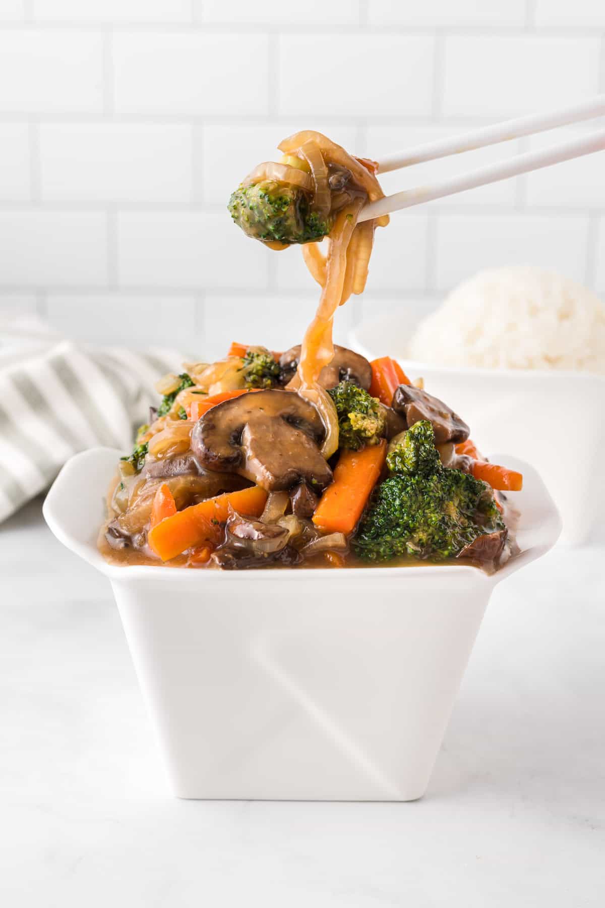 chopsticks taking teriyaki vegetables from a takeout container