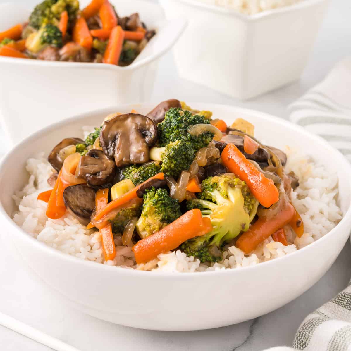 teriyaki vegetables over white rice in a bowl