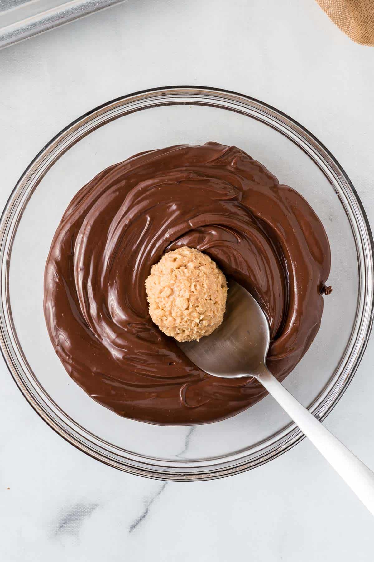 dipping a peanut butter ball into melted chocolate