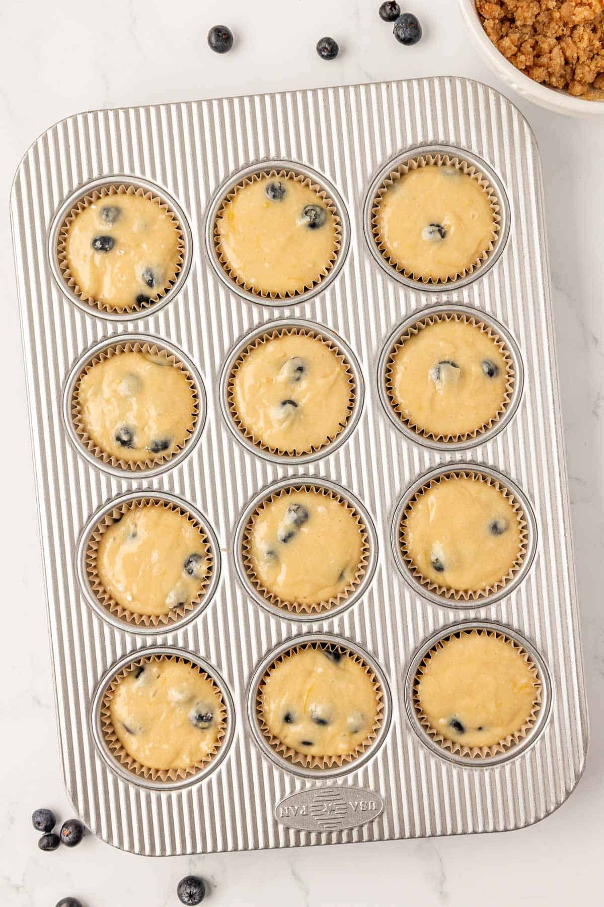 blueberry muffin batter in a muffin tin
