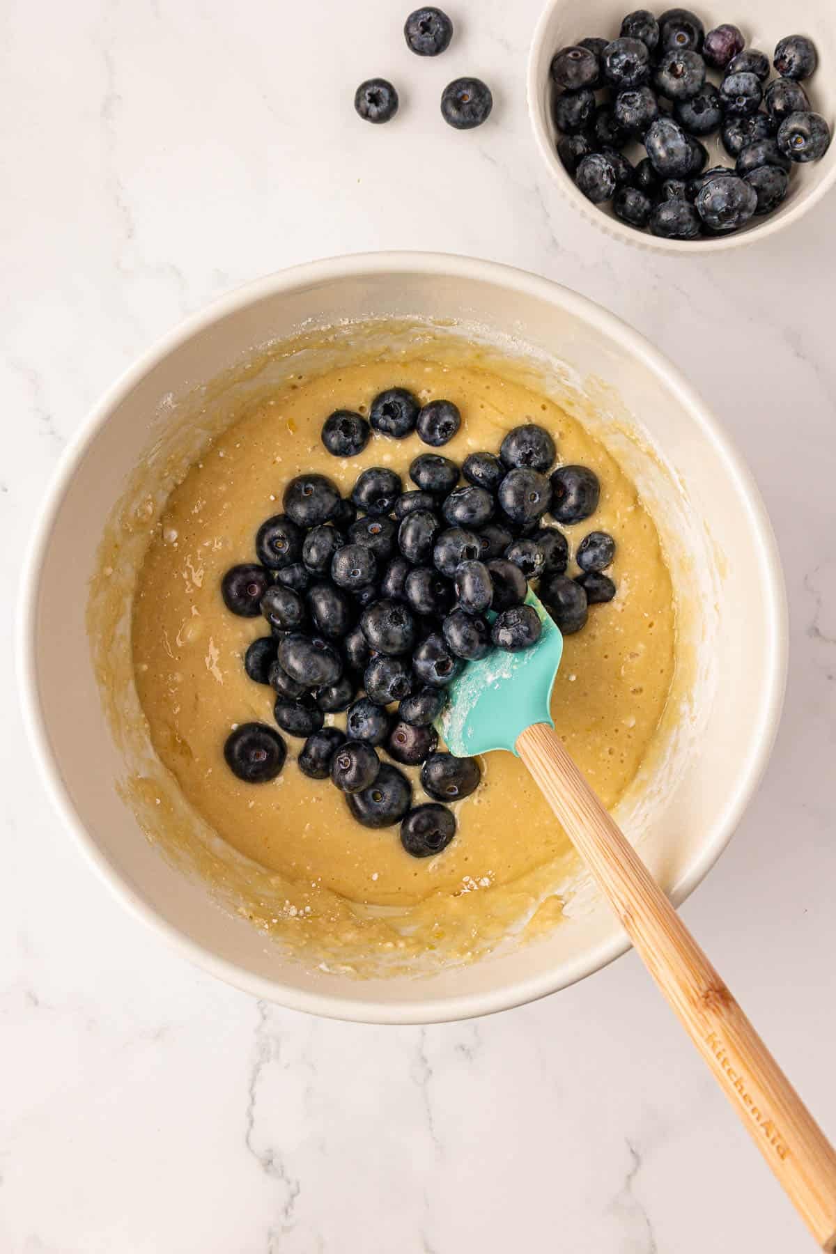 stirring the blueberries into the muffin batter