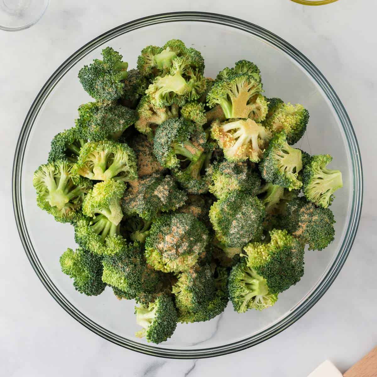 adding the oil and spices to the broccoli