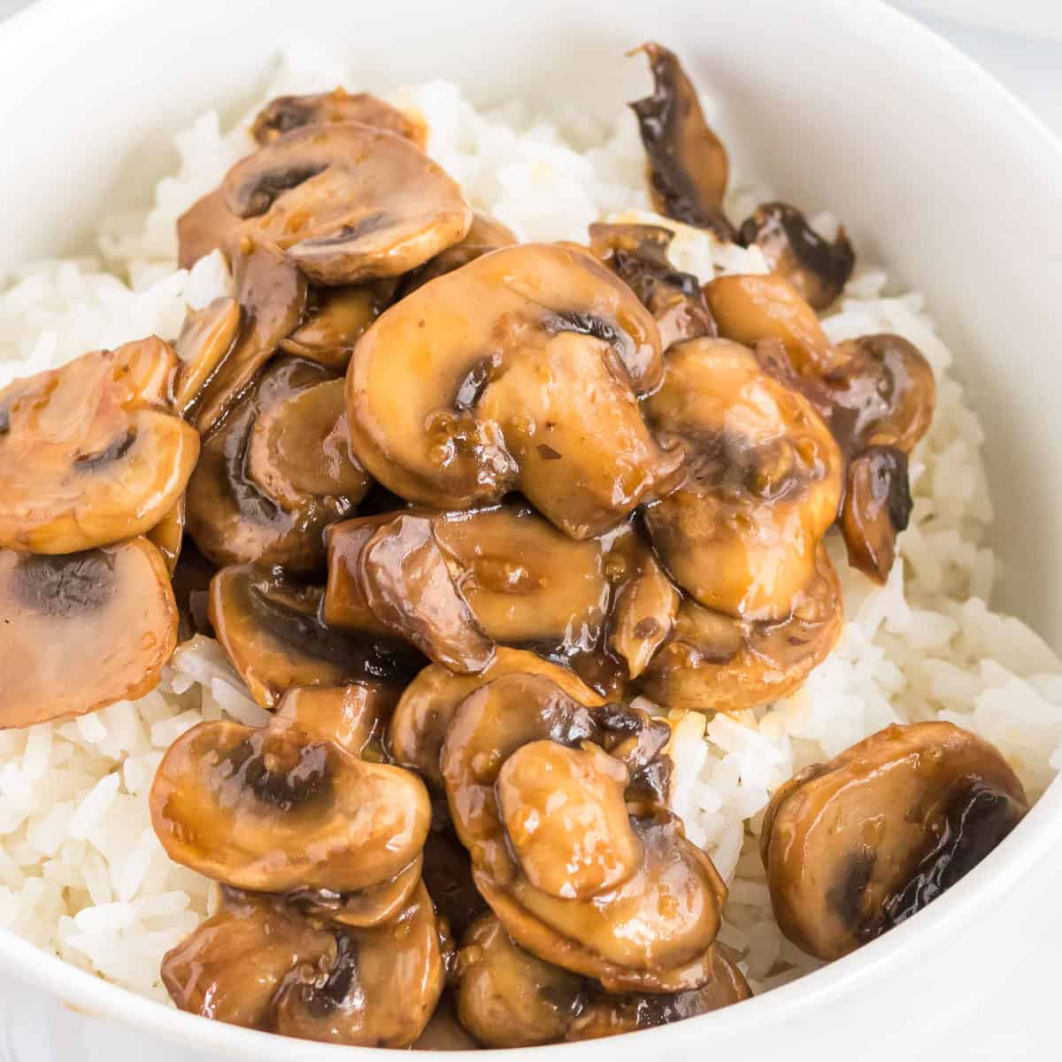 teriyaki mushrooms over rice in a white bowl