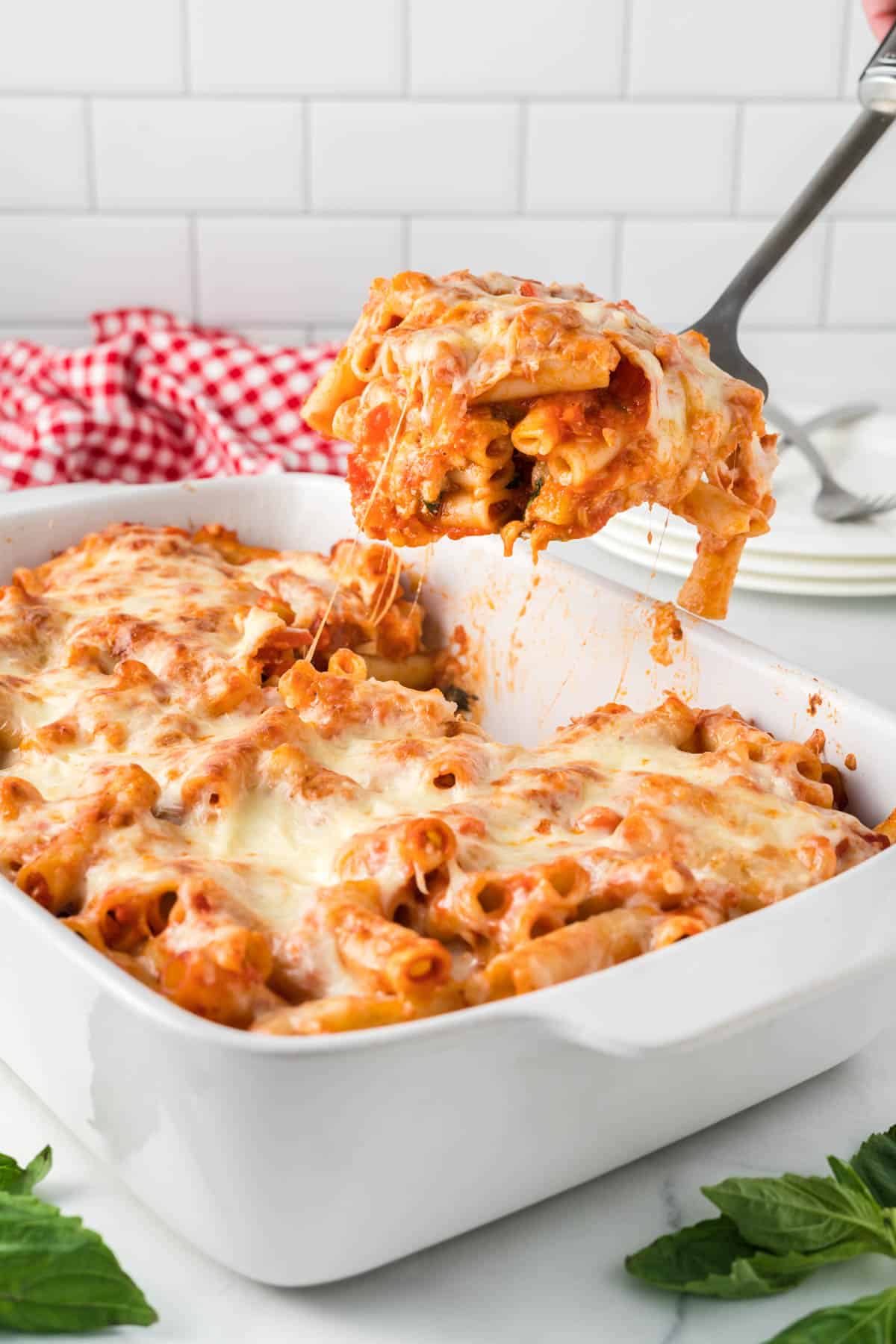 taking a scoop of vegetarian baked ziti from the casserole dish