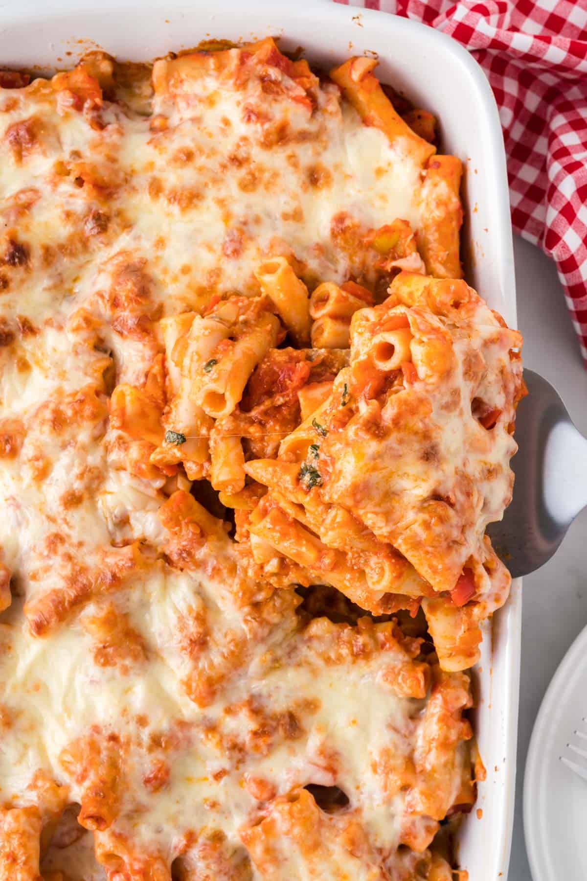 taking a scoop of vegetarian baked ziti from the casserole dish