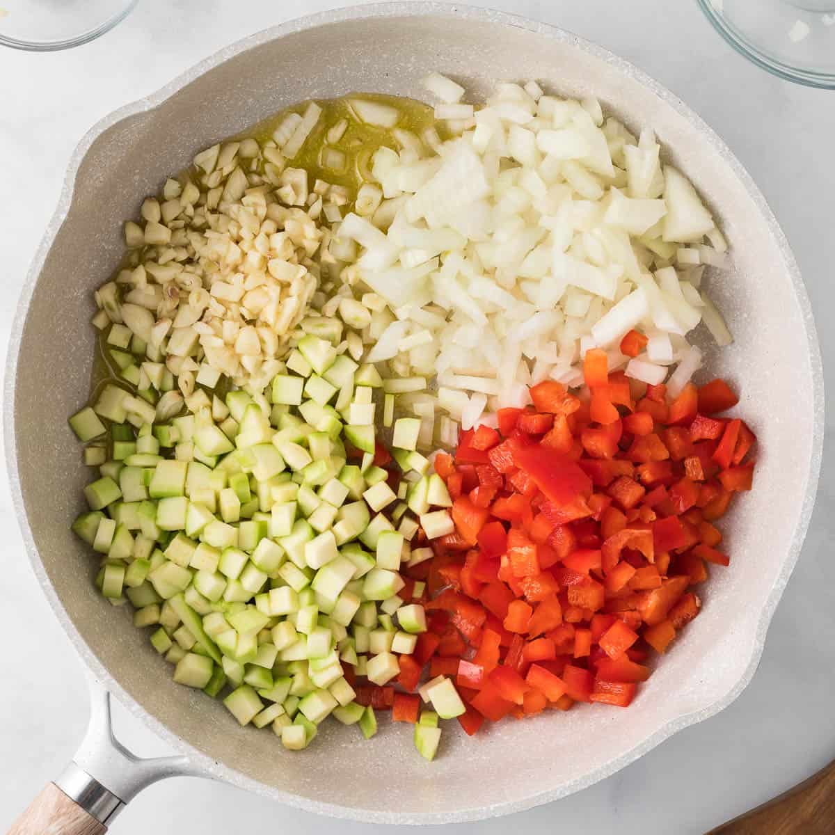 adding the bell pepper, onion, garlic, and squash to the skillet