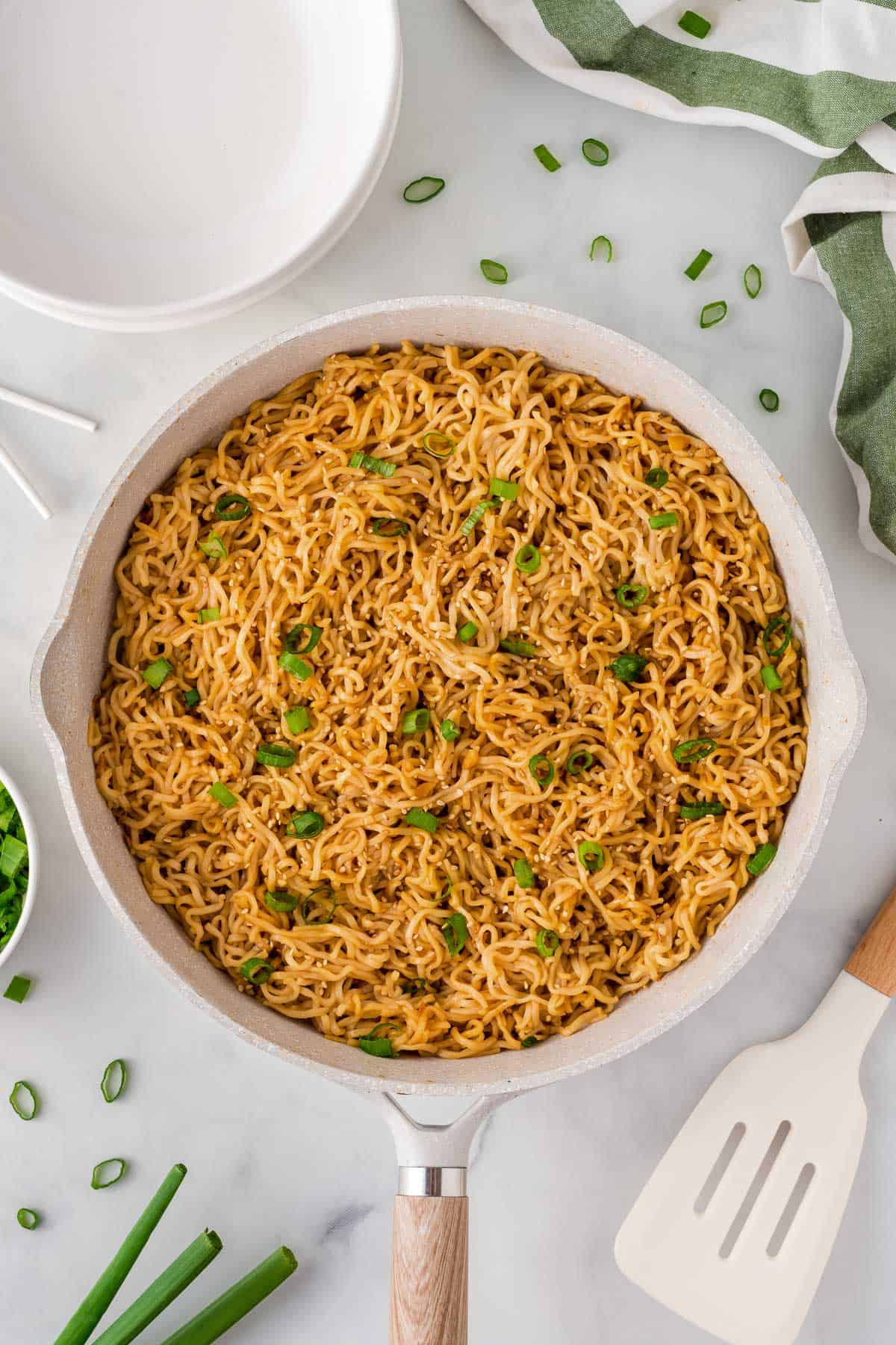 garlic ramen noodles in a skillet topped with green onions