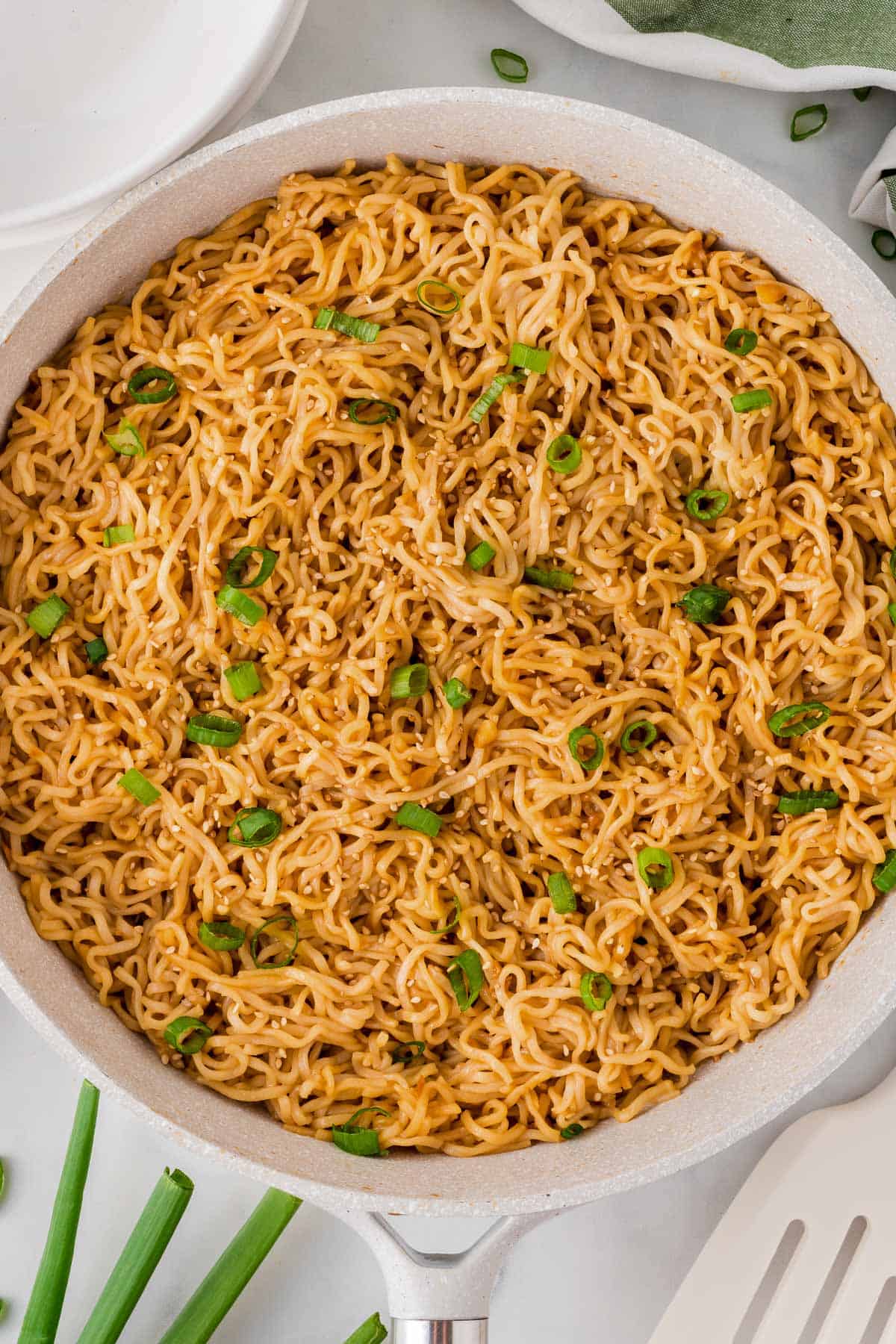 garlic ramen noodles in a skillet topped with green onions