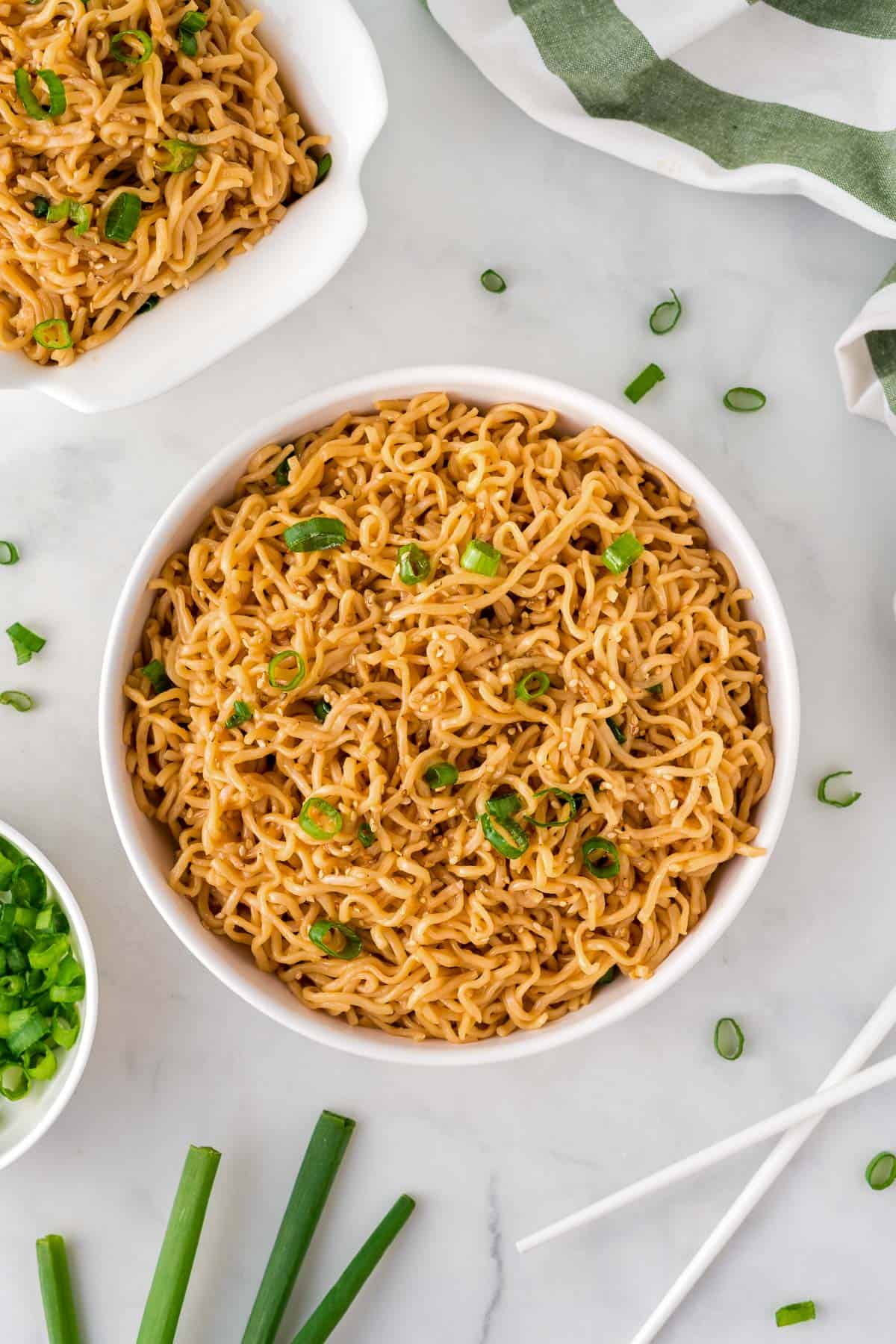 sesame garlic ramen noodles in a white bowl topped with green onions