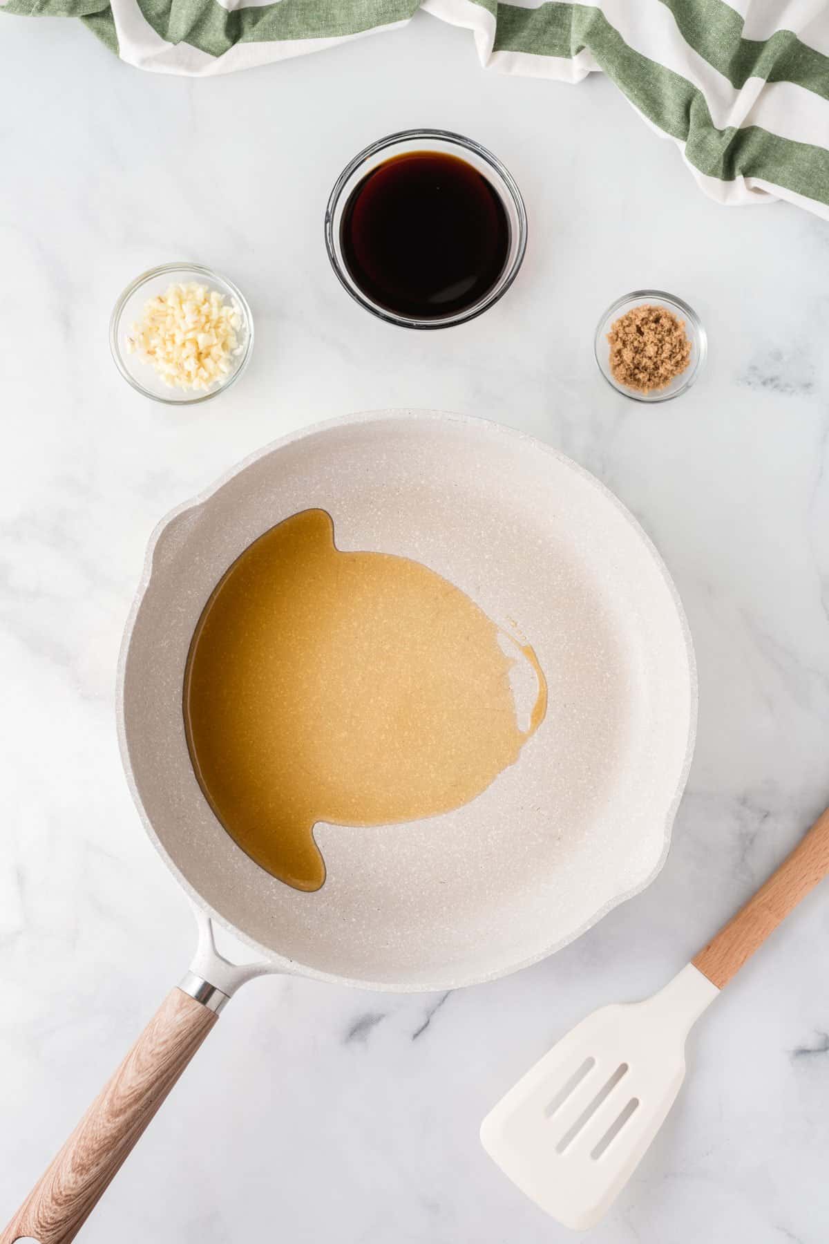 oil in a pan next to minced garlic, soy sauce, and brown sugar