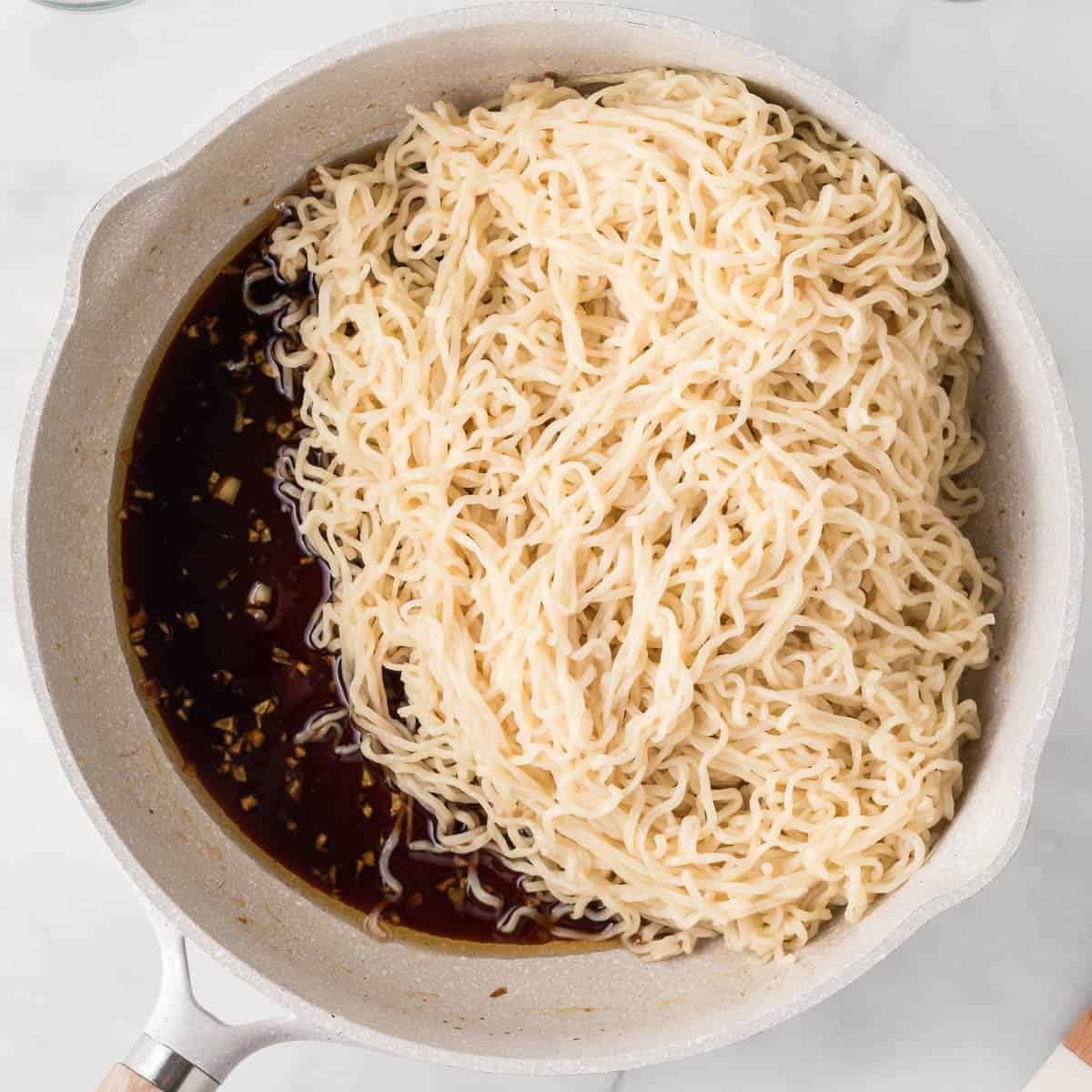 adding the cooked ramen noodles to the sesame garlic sauce