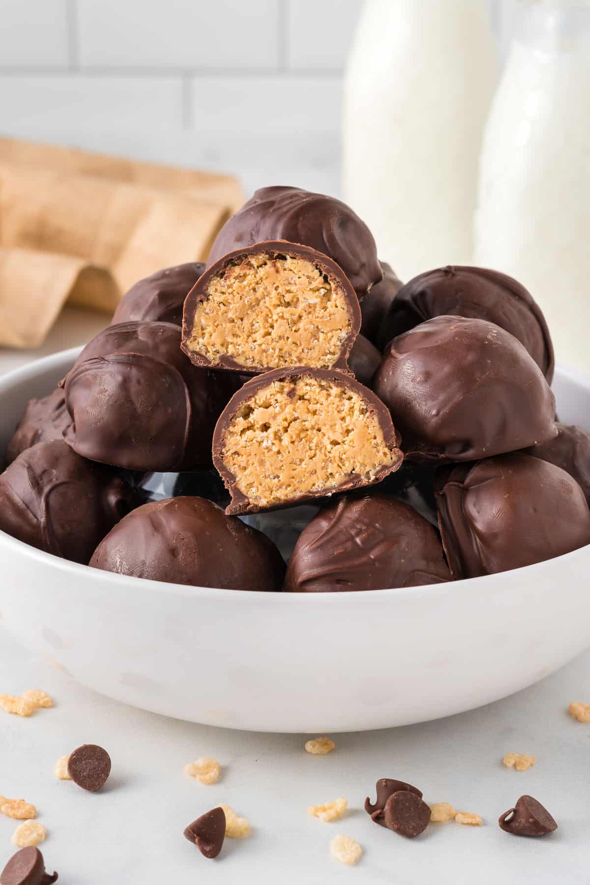 peanut butter balls stacked in a bowl, with one cut open