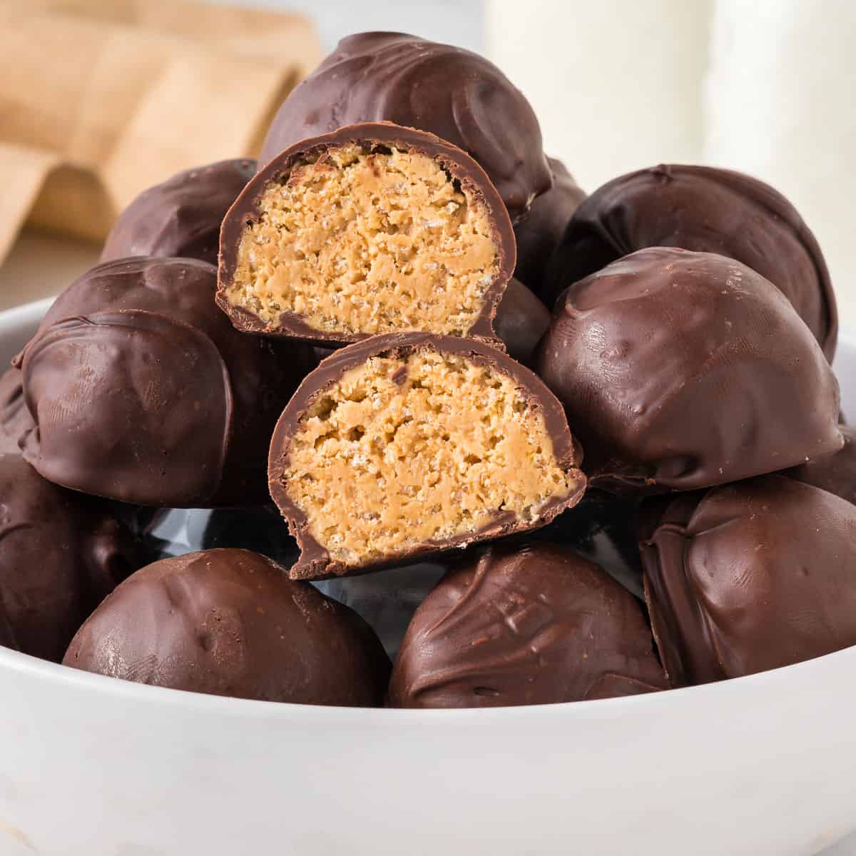 peanut butter balls stacked in a bowl, with one cut open
