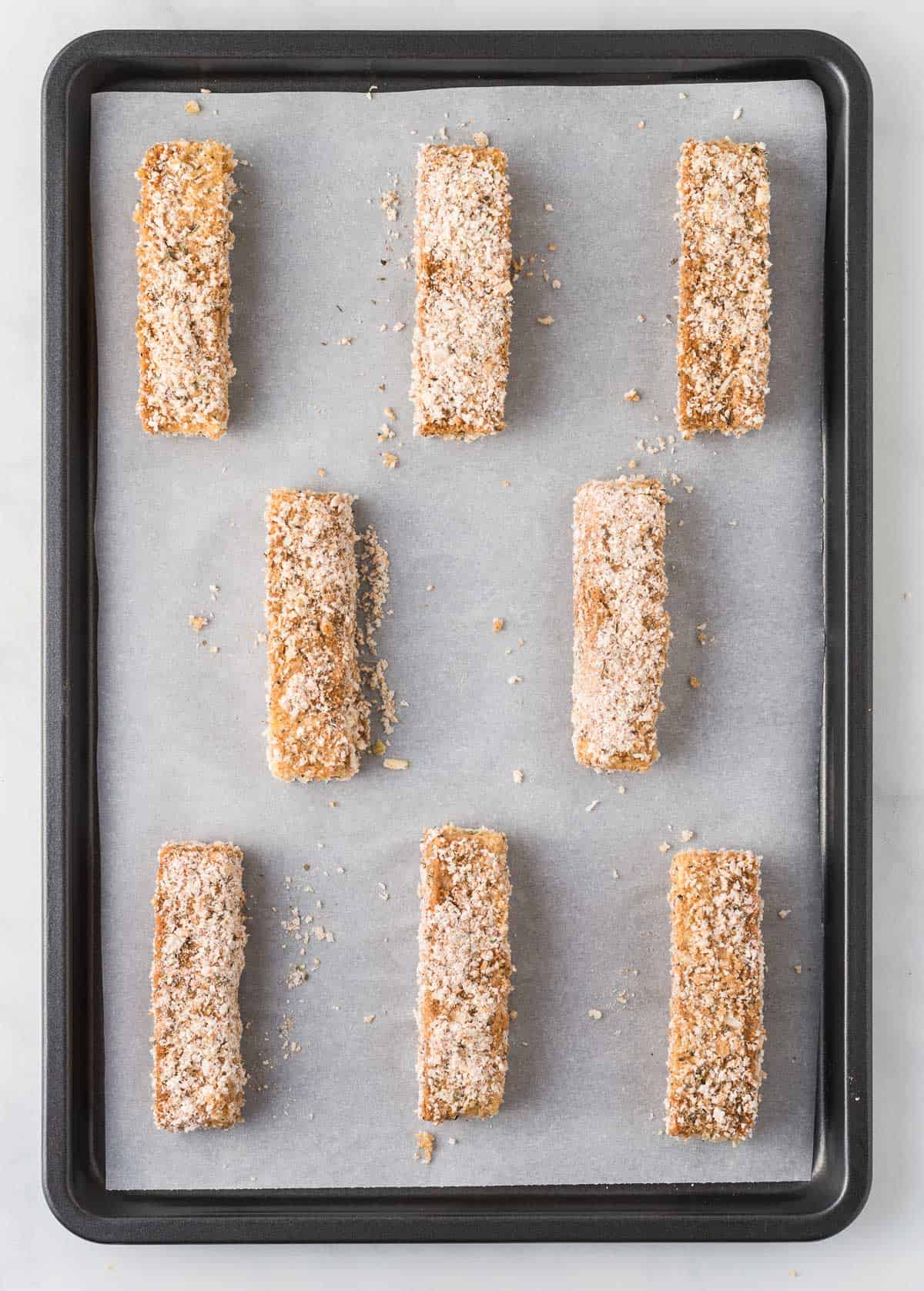 breaded tofu strips on a lined baking sheet