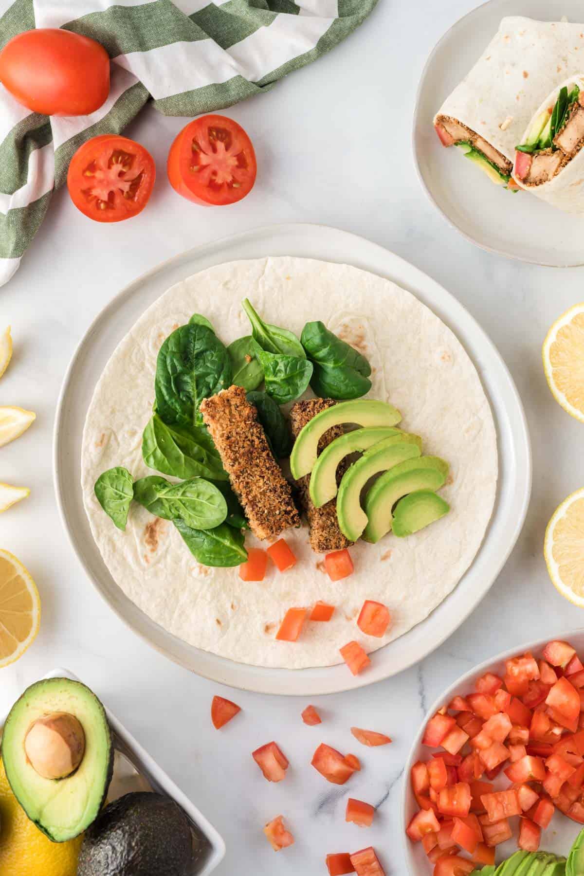 tofu wrap open showing the avocado, spinach, tomato, tofu, and lemon