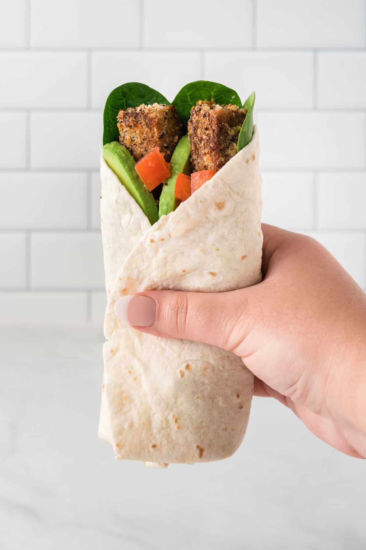 hand holding a tofu wrap