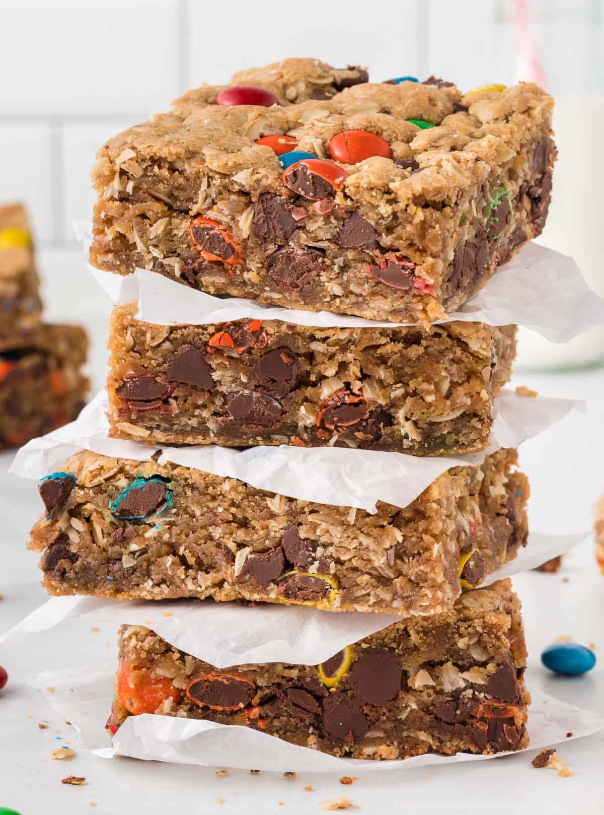 monster cookie bars stacked between pieces of parchment paper