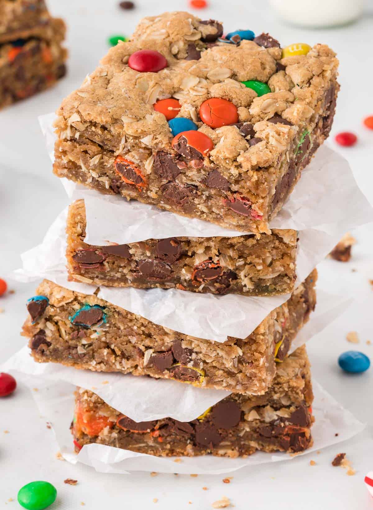 monster cookie bars stacked between pieces of parchment paper