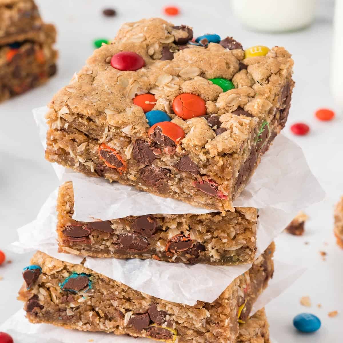 monster cookie bars stacked between pieces of parchment paper
