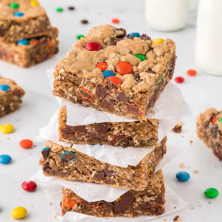 monster cookie bars stacked between pieces of parchment paper