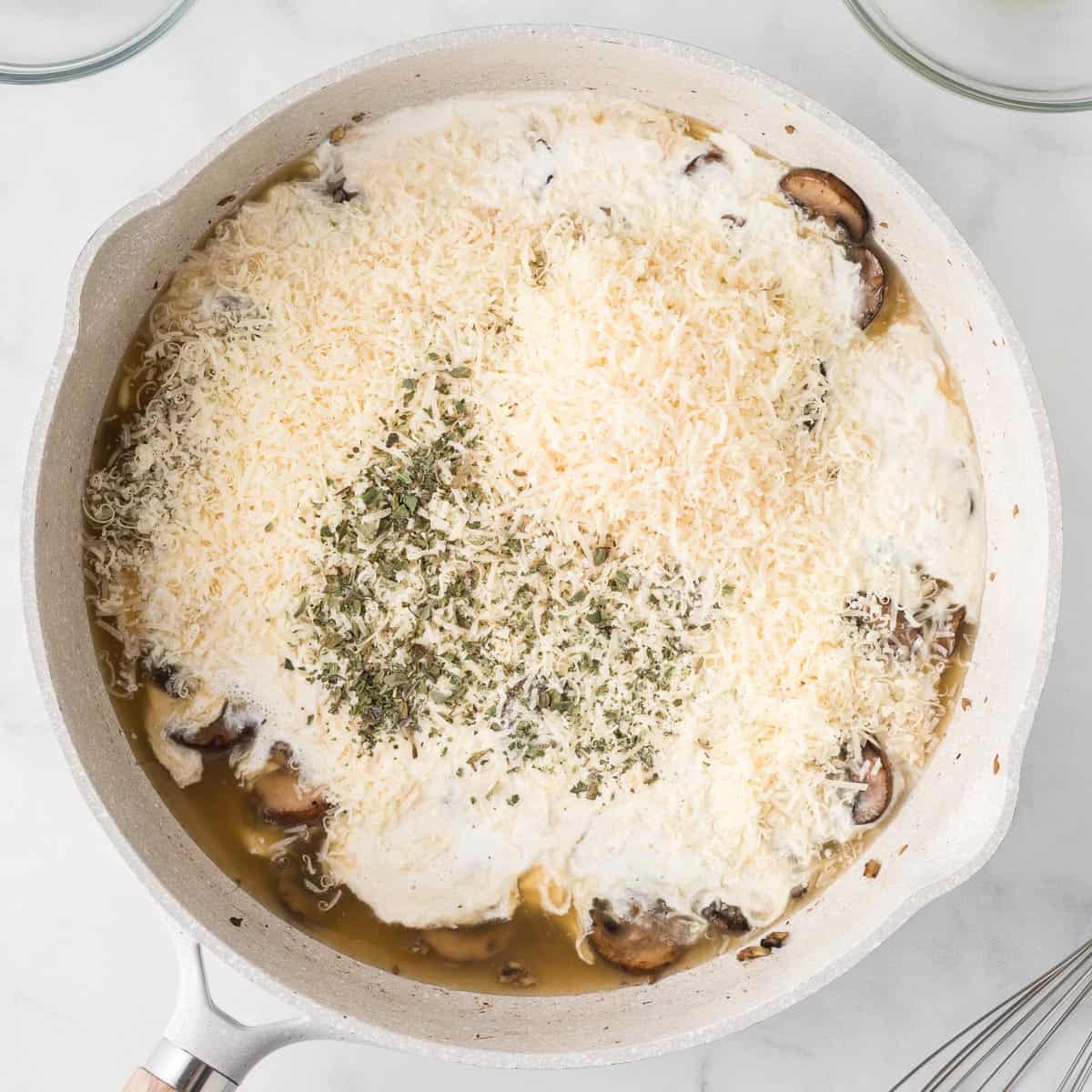 adding the heavy cream, parmesan cheese, and spices to the mushrooms