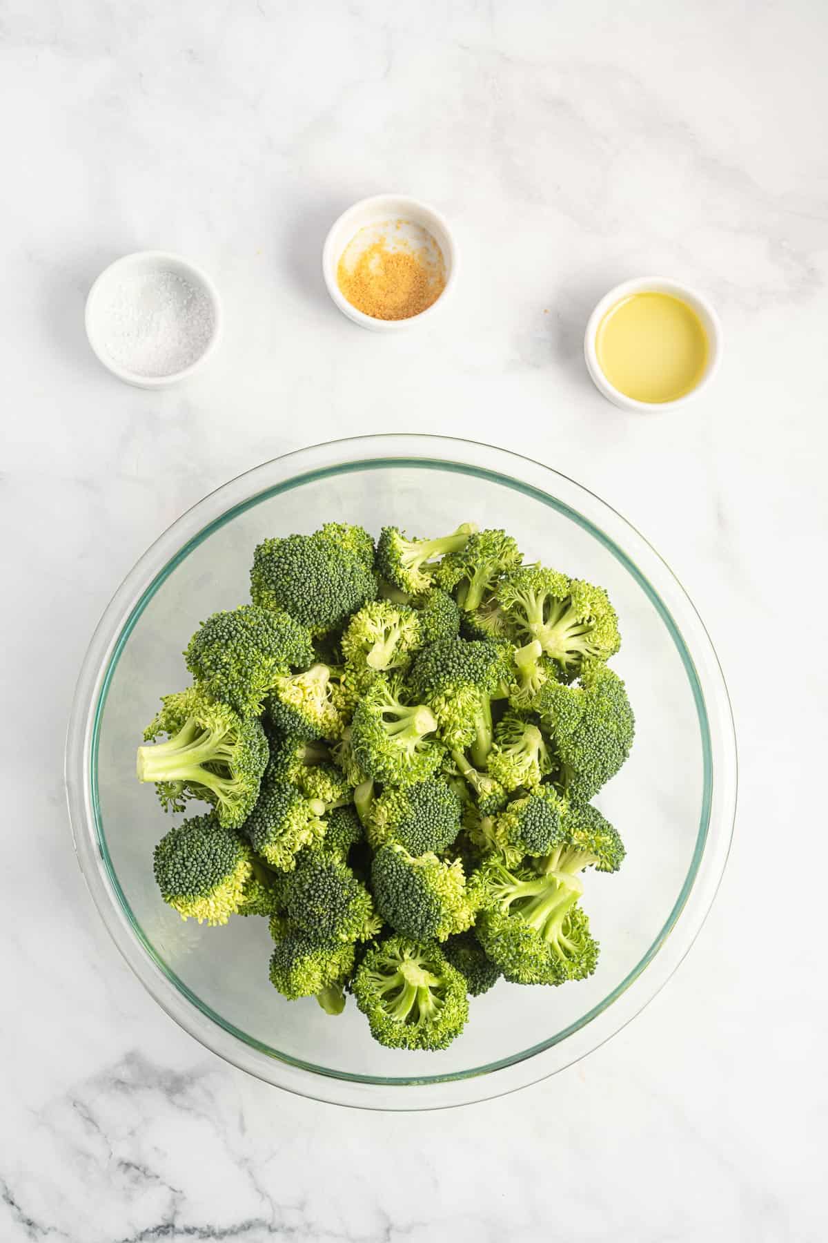 broccoli florets in a bowl surrounded by the spices