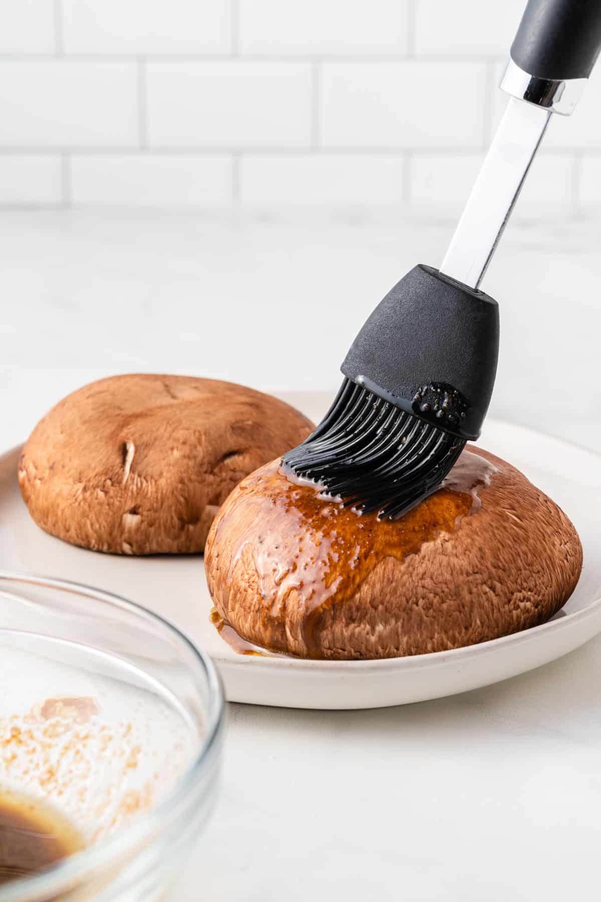 using a basting brush to cover the mushrooms in liquid