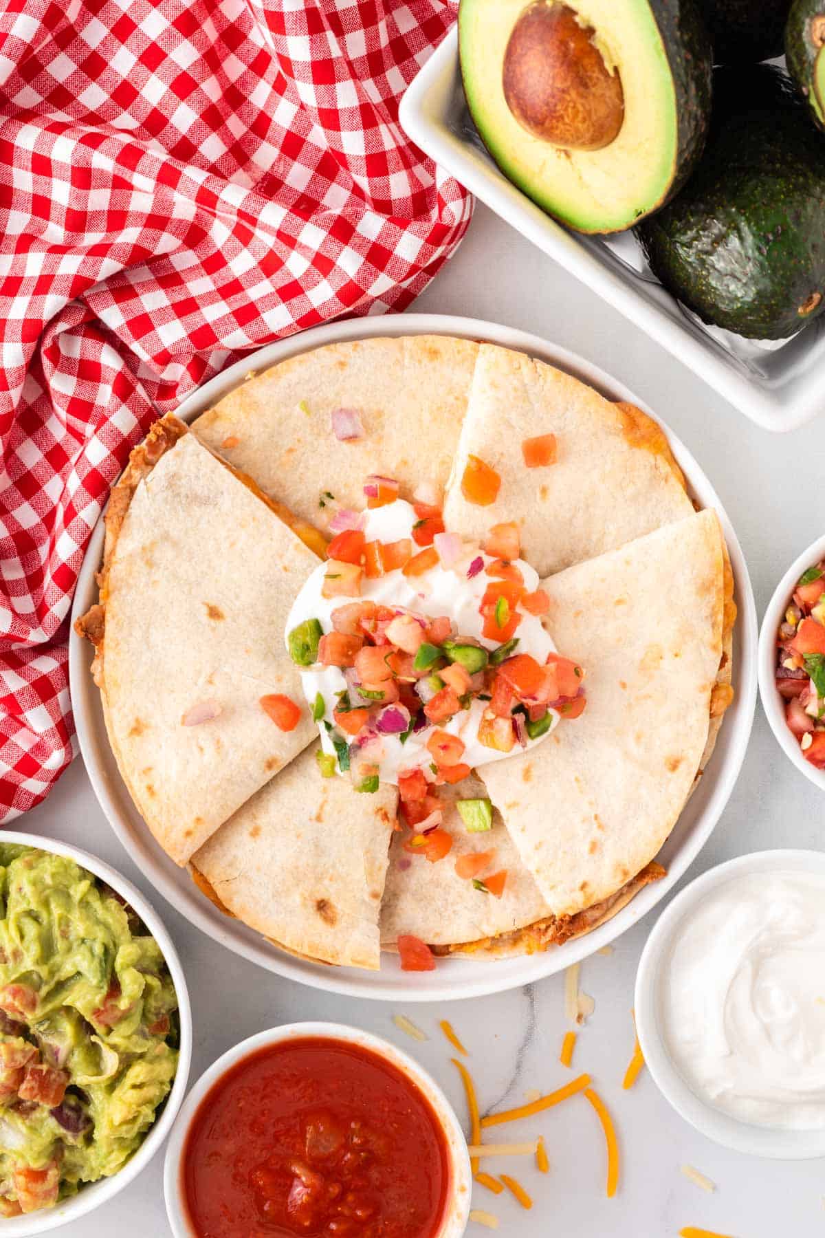 quesadillas on a plate topped with sour cream and pico