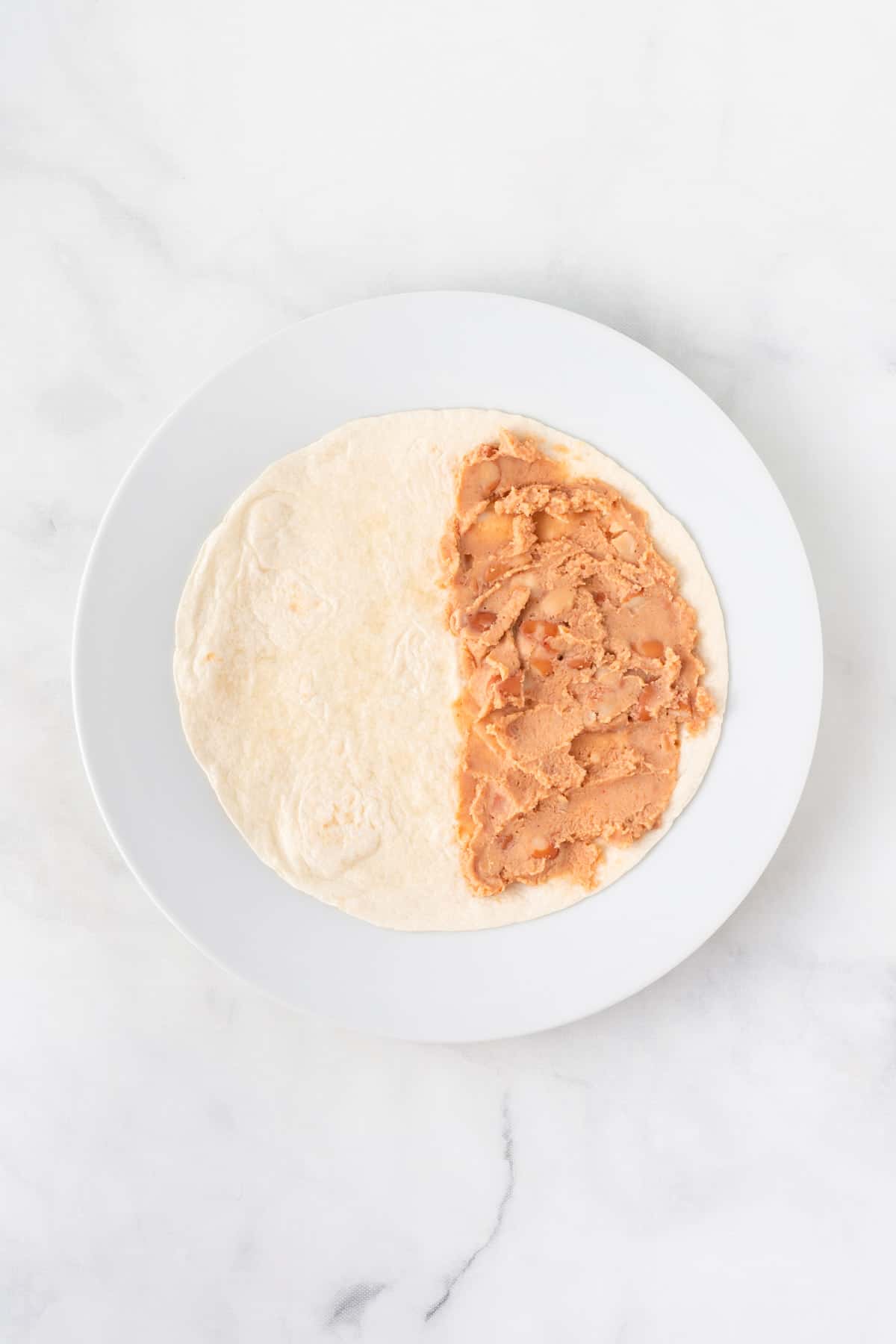 soft taco shell half spread with refried beans